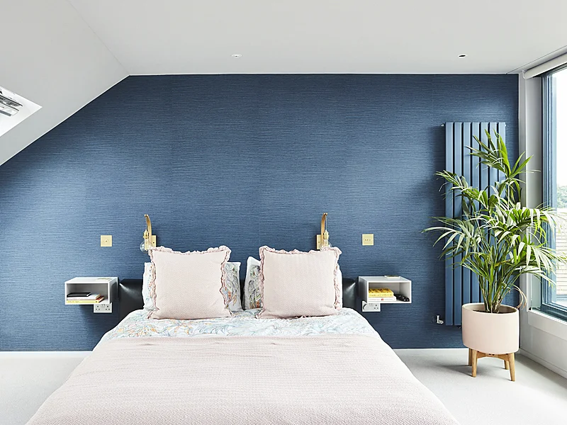 Calming blue bedroom with textured wallpaper and pale pink bedding