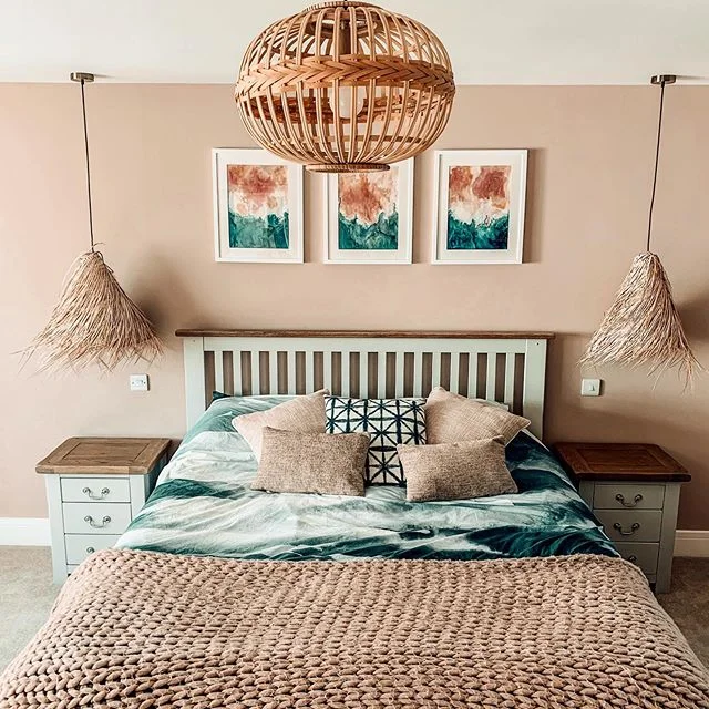Muted pink bedroom with green accents and rattan lampshades in a country boho style