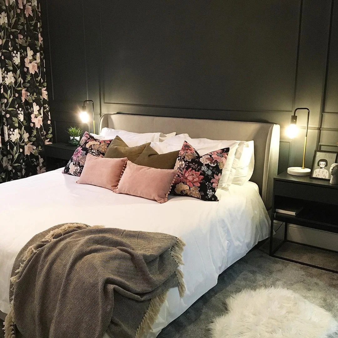 Bold black bedroom with panelling and soft pink curtains and cushions