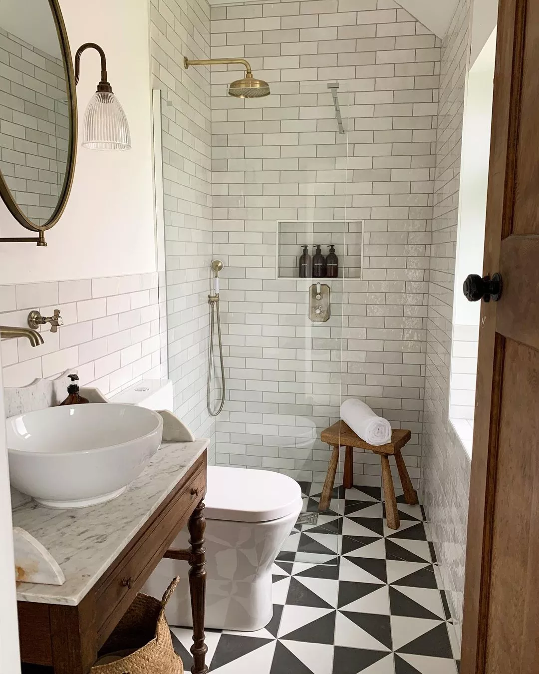 Small bathroom with walk-in shower featuring white tiles and brass fixtures